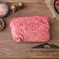 Raw ancestral ground beef with organ meat on a wooden cutting board with Wyoming Pure branding, surrounded by spices and a small bowl of organ meat